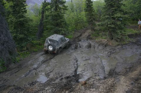 2003 Jeep TJ - Off-roading adventure: a Jeep TJ navigates a challenging muddy track in a forest.
