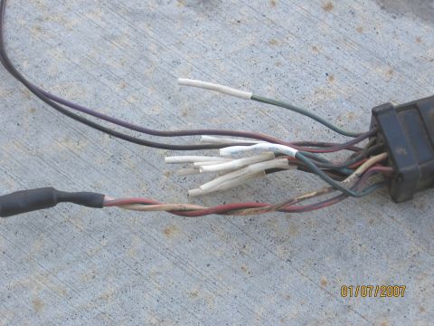 1994 Ford Bronco - A close-up view of a vehicle's wiring harness, showing multiple wires and a connector, laid out on a concrete surface.