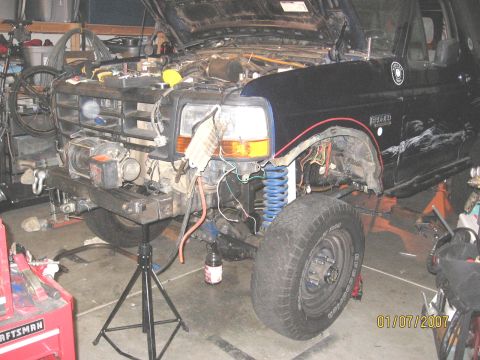 1994 Ford Bronco - Front view of a 1994 Ford Bronco being worked on in a garage, showing the engine bay and suspension.