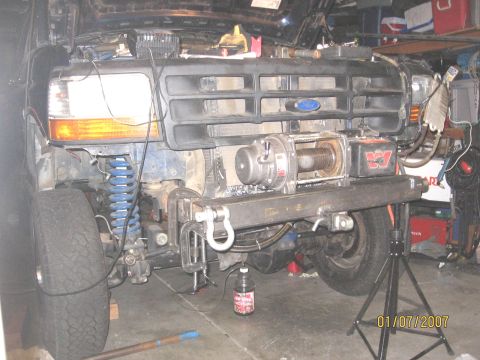 1994 Ford Bronco - The front end of a Ford truck is disassembled, revealing a winch and suspension components.