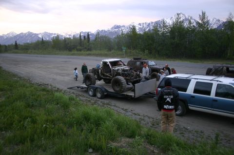 2003 Jeep TJ - Several vehicles and people gathered near a trailer with a custom buggy, with snow-capped mountains in the distance.