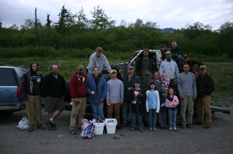 2003 Jeep TJ - A group of people gathered around a camouflage-painted truck and a blue SUV, likely at an outdoor event.