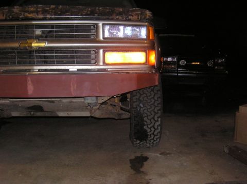 2000 Chevrolet Tahoe - A maroon and brown Chevrolet truck's front end is visible, with another dark vehicle in the background.