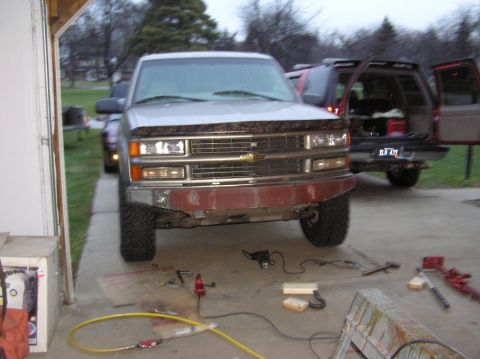 2000 Chevrolet Tahoe - A silver Chevrolet pickup truck is parked in a garage with tools scattered around its front end.