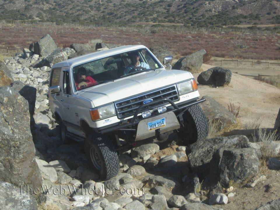 White Ford Bronco navigating a rocky trail. License plate reads HOV 554