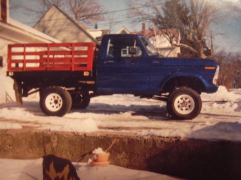 1977 Ford F-150 - A blue pickup truck with a red flatbed is parked on a snowy surface.