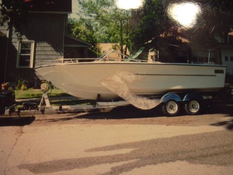 1977 Ford F-150 - A white boat is parked on a trailer on a residential street.