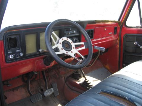 1974 Ford F-100 - The interior of an older truck shows a worn seat and aftermarket steering wheel with a GT emblem.