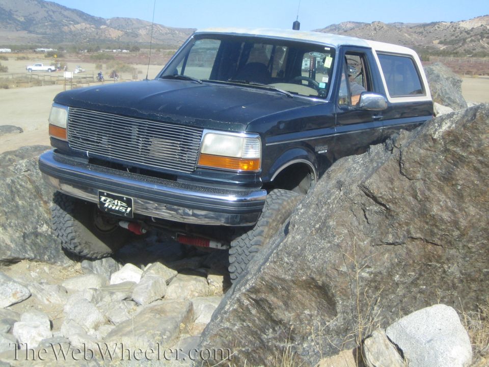 Dark blue SUV with white top on rocks, front grille visible