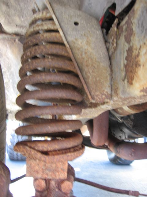 1974 Ford F-100 - Underside view of a rusty coil spring and associated suspension components.