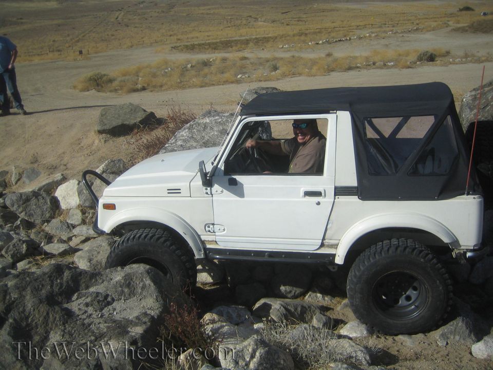 White 1987 Suzuki Samurai navigating rocky terrain