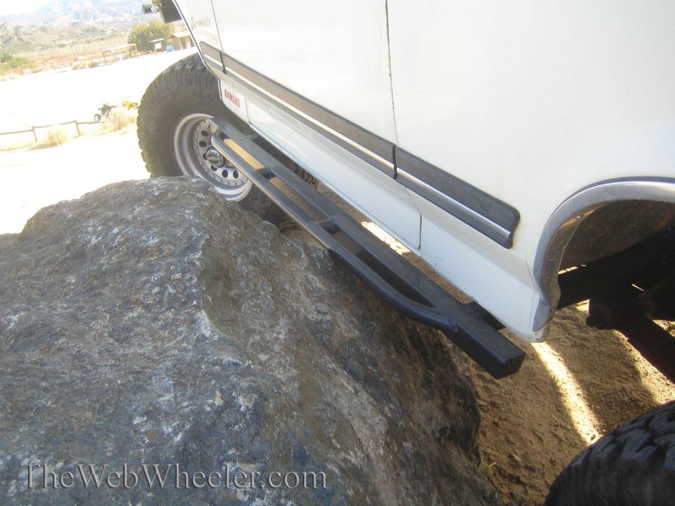 White SUV side steps and off-road tire on a large rock