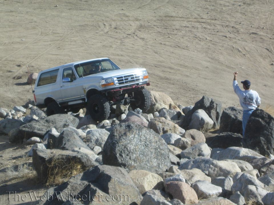 Silver SUV with lifted suspension and large tires navigating a rocky incline