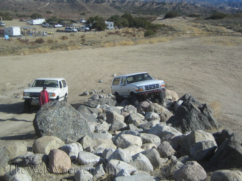 White SUV navigating rocky terrain, another white SUV parked nearby