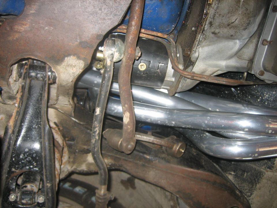 Exhaust manifold pipes and starter motor on a vehicle underside