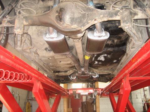 1976 Ford Ranchero - The vehicle's undercarriage and exhaust system are visible while on a red hydraulic lift.