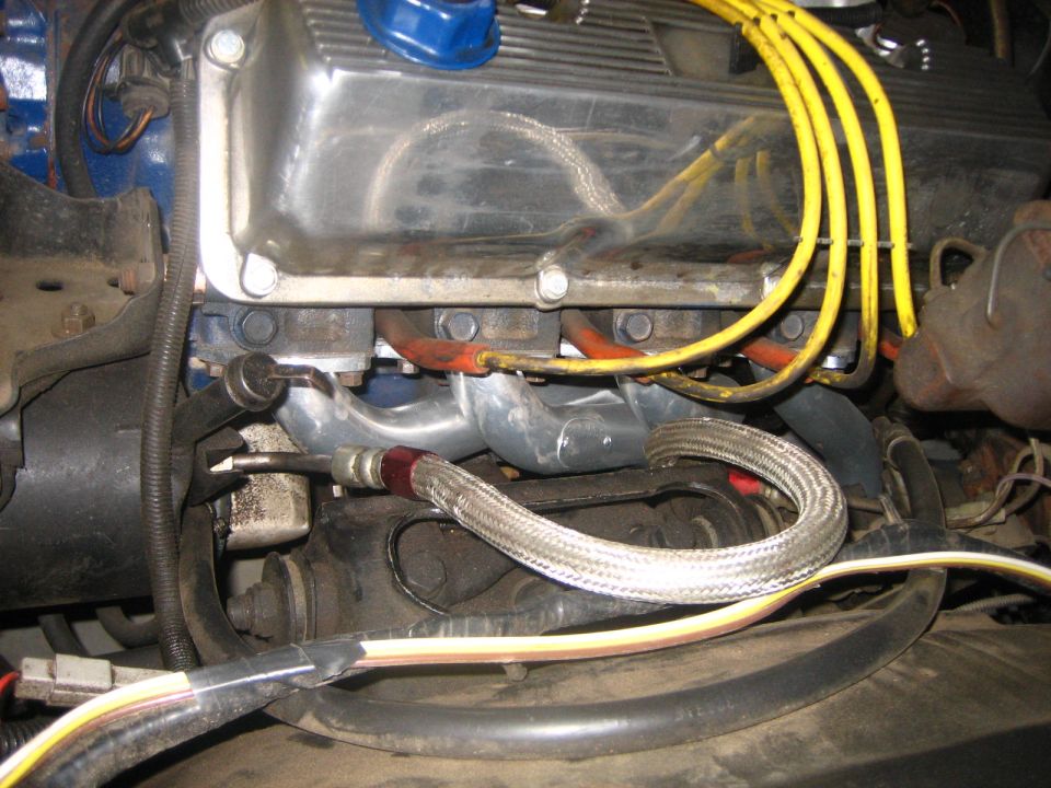 Engine exhaust manifold with yellow spark plug wires and braided metal hose