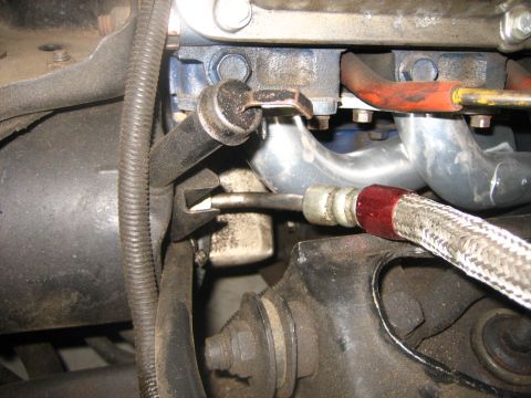 1976 Ford Ranchero - Close-up view of an engine's exhaust manifold and a braided hose, likely part of the fuel or oil system.