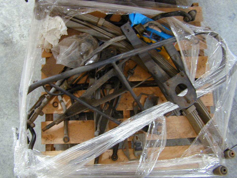 Pallet of used leaf springs, radius arms and suspension brackets wrapped in plastic