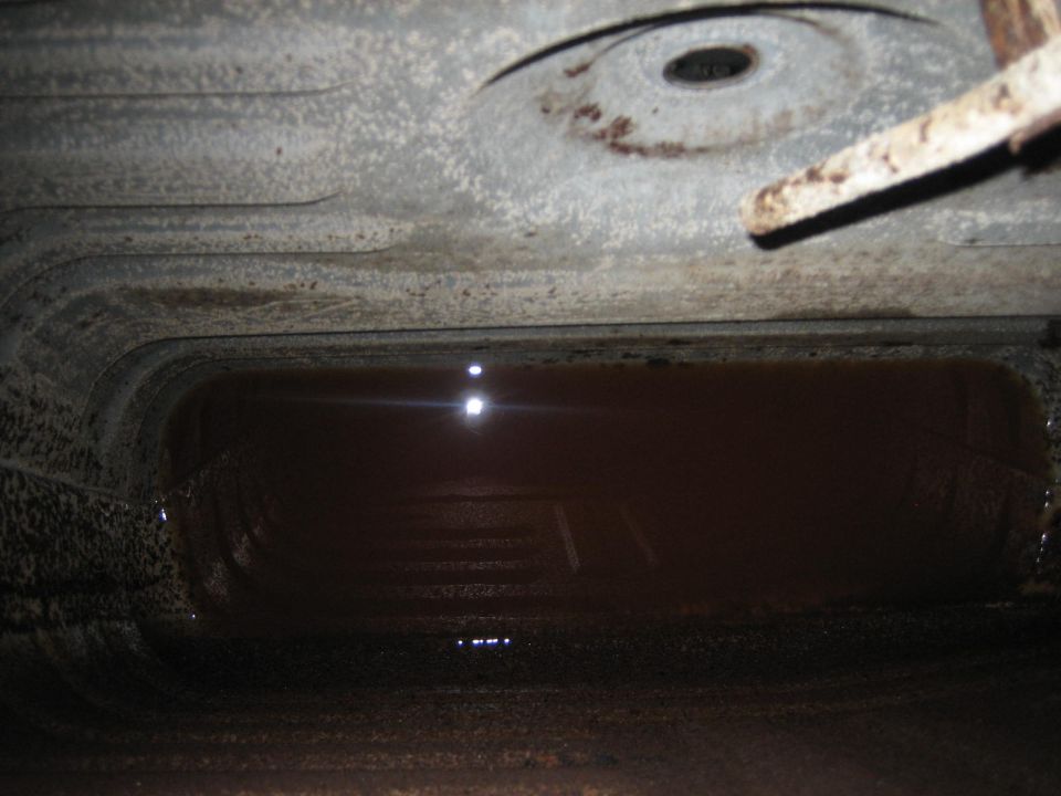 Underside view of a vehicle's gas tank with liquid inside