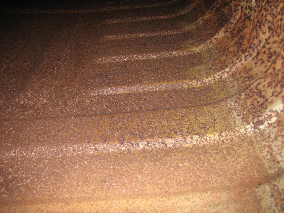 Interior view of heavily rusted metal with horizontal ridges