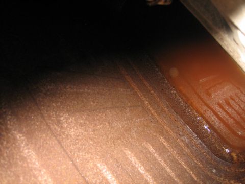 1976 Ford Ranchero - The image shows a close-up view of a rusty metal surface with a small amount of reddish liquid.