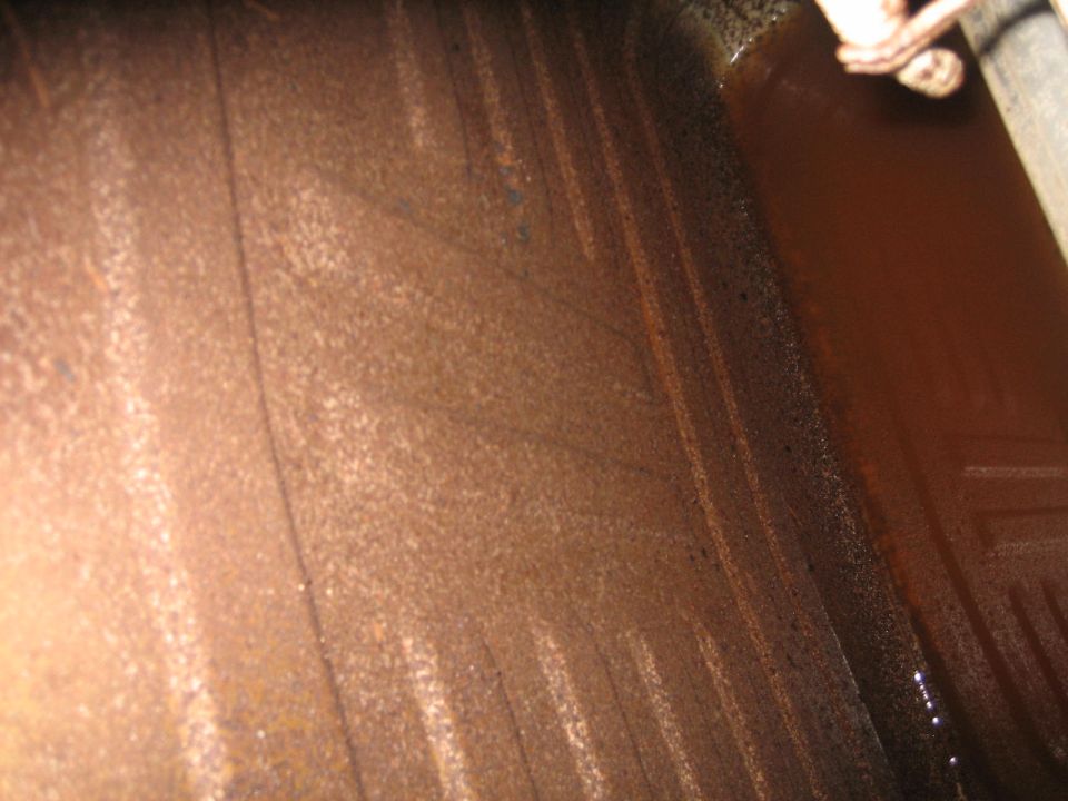 Rusty gas tank interior with visible lines and dark liquid
