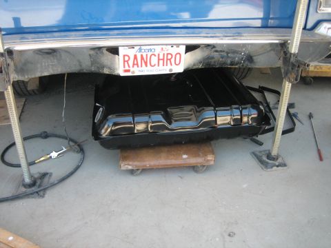 1976 Ford Ranchero - A new gas tank is being installed under a vehicle, supported by a dolly and jacks.