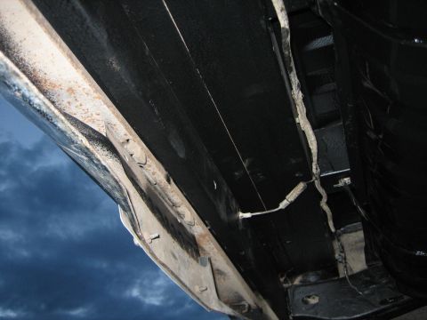 1976 Ford Ranchero - Close-up view of the undercarriage of a vehicle, revealing the frame and black protective coating.