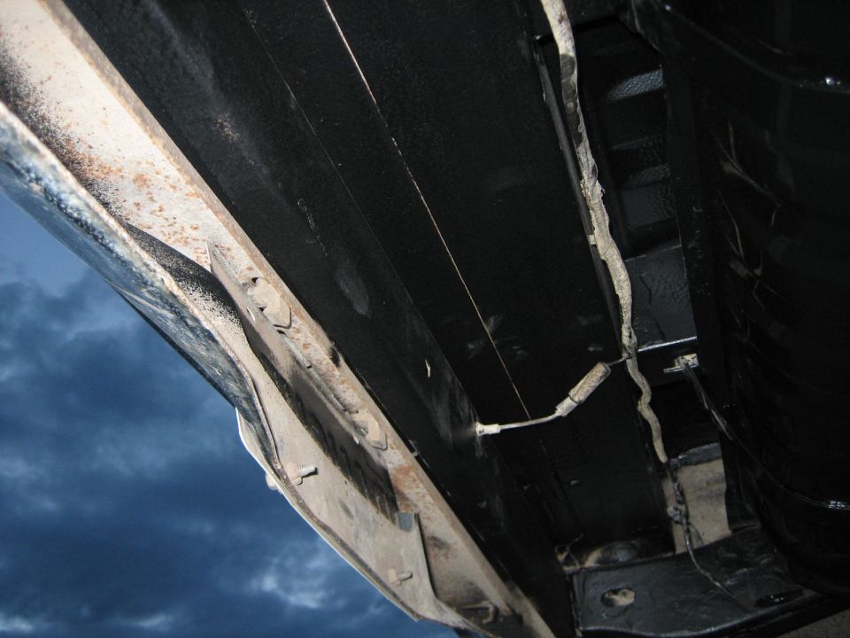 Underside of vehicle showing frame and black undercoating