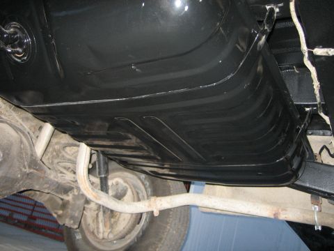 1976 Ford Ranchero - The underside of a vehicle shows a black gas tank and part of the exhaust system.