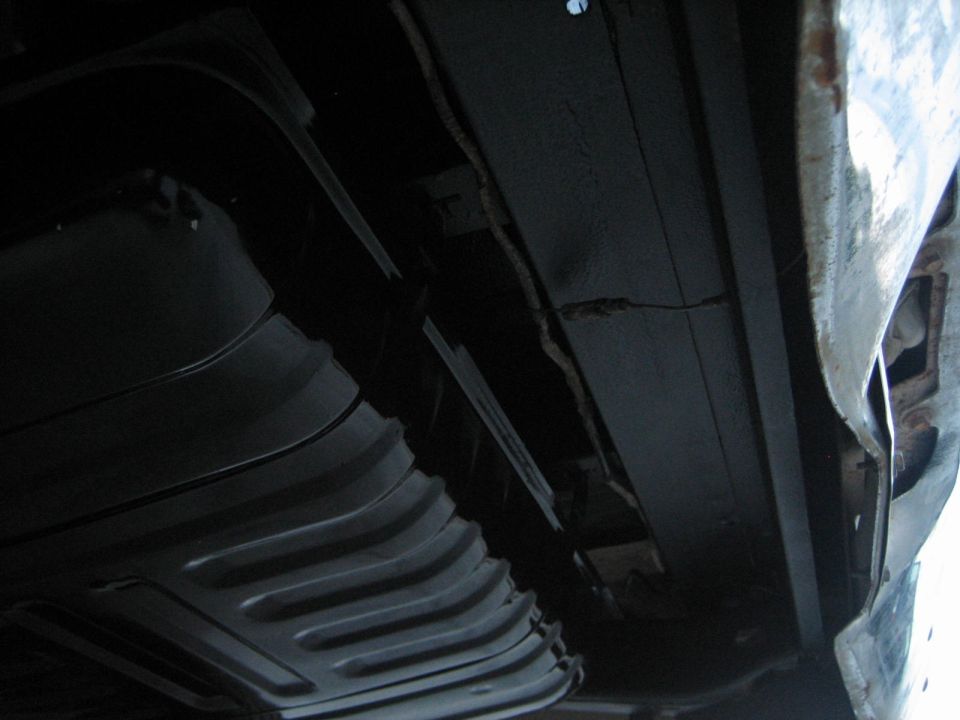 Underside of a vehicle showing a ribbed fuel tank and frame rails