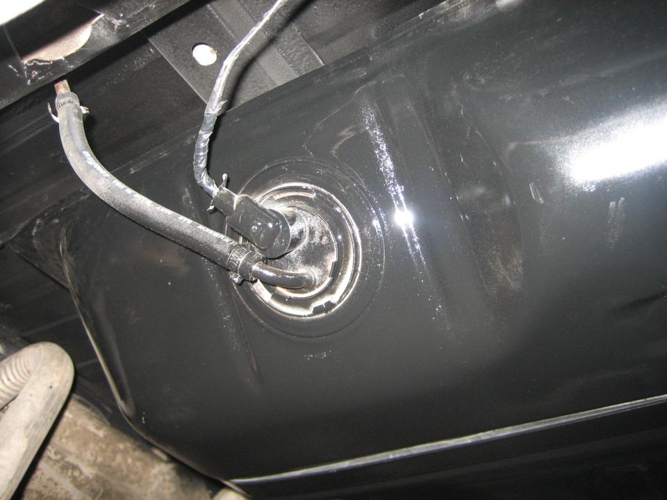 Underside view of a black fuel tank with fuel lines connected to the sending unit
