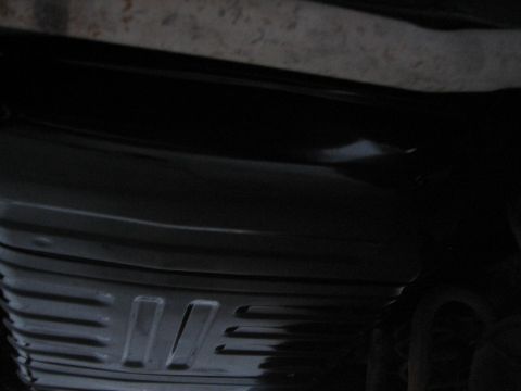 1976 Ford Ranchero - A close-up view of the underside of a vehicle, focusing on a dark, ribbed metal part.