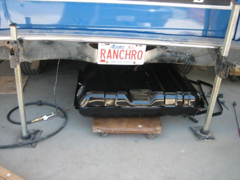 1976 Ford Ranchero - A black gas tank is visible under the rear of a blue vehicle, which has an Alberta license plate.