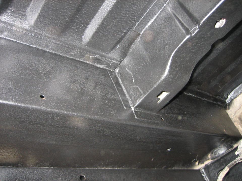 Close-up of black undercoating on vehicle frame and floor pan