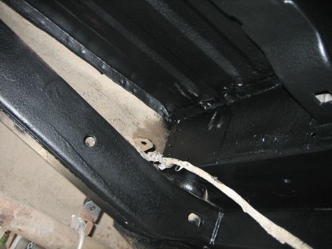 1976 Ford Ranchero - The undercarriage of a vehicle shows extensive black protective coating on its frame and body panels.