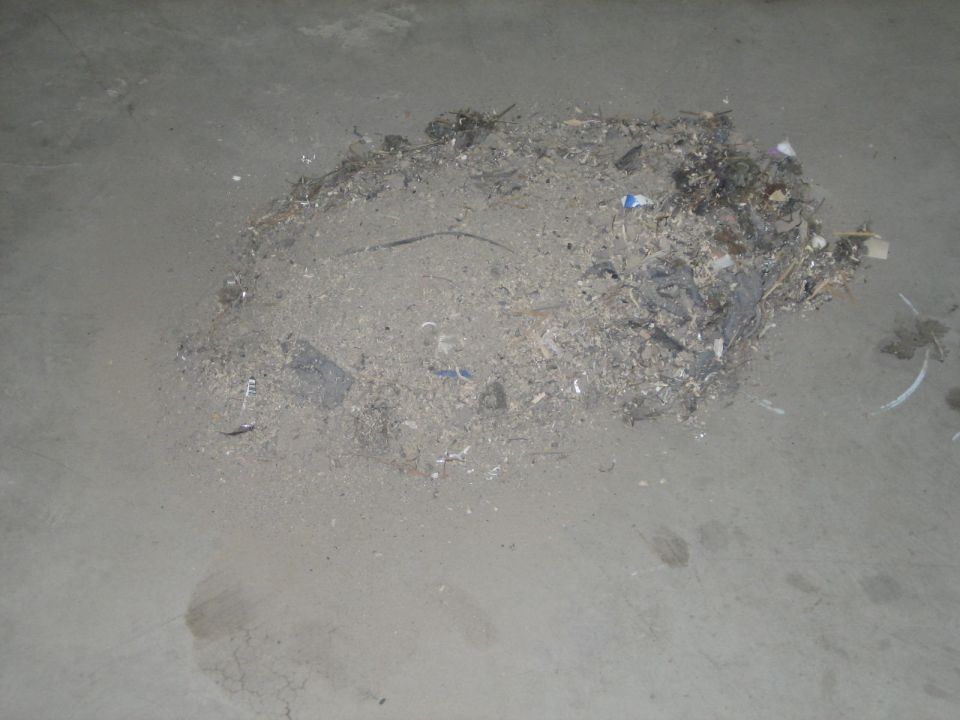 pile of dirt, dust, and debris on a concrete floor