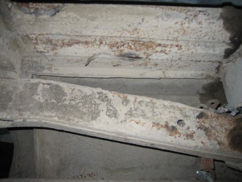 1976 Ford Ranchero - The underside of a vehicle shows significant rust and wear on its frame components.