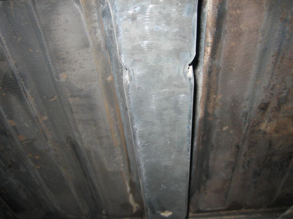 Underside view of vehicle frame with ribbed panels and support beam