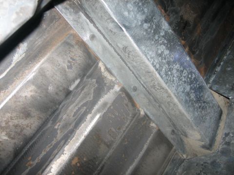 1976 Ford Ranchero - Close-up view of the underside of a vehicle's frame, showing ribbed metal construction and weld marks.