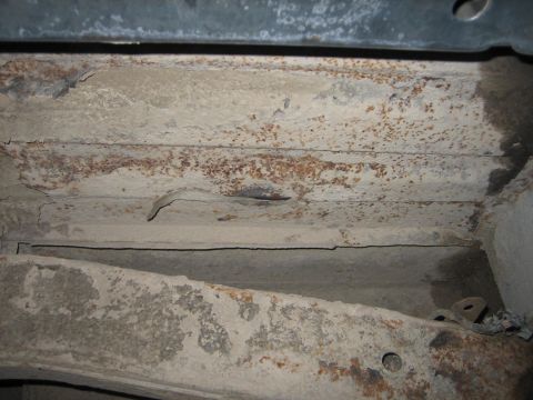 1976 Ford Ranchero - The underside of a vehicle shows significant rust and deterioration on its structural components.