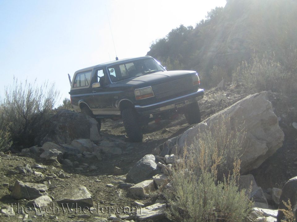 Ford Bronco navigating a rocky trail with the front right tire high off the ground