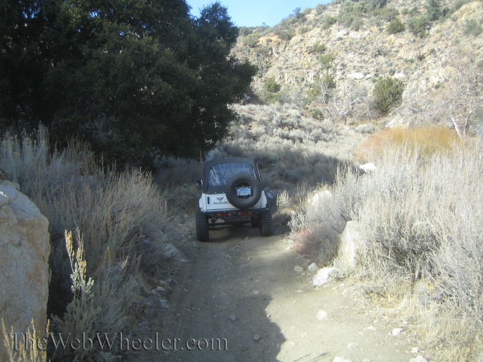 White 1987 Suzuki Samurai parked on a dirt road in a dry, hilly landscape