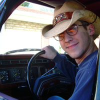 1984 Ford Bronco - A man in a cowboy hat smiles while sitting behind the steering wheel of a vehicle.