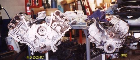 1974 Ford Bronco - Two V8 engines are displayed, one identified as a 4.6 DOHC, in a workshop setting.