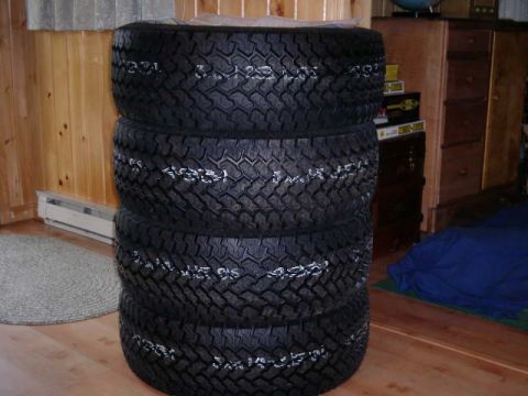 1984 Ford Bronco - A stack of four tires, each with white lettering indicating size 33x12.50R15, is shown indoors.