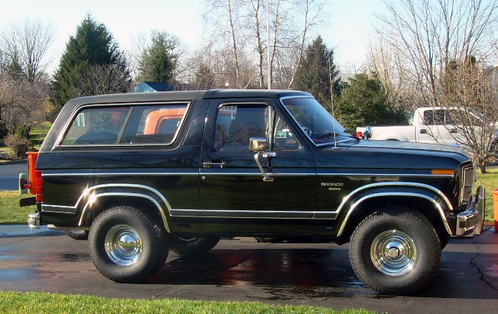 Black two-door Ford Bronco SUV parked in side profile on a wet driveway