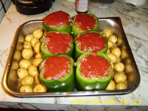 1989 Ford Bronco - A metal baking tray holds six green bell peppers stuffed with a meat and rice mixture, covered in tomato sauce, and surrounded by small, wh…