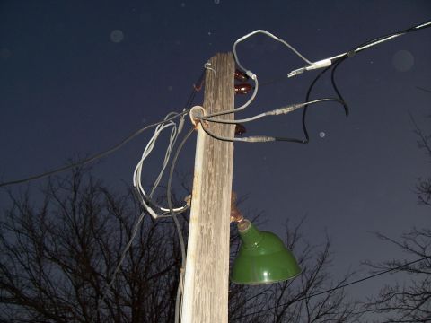 2004 Aston Martin Virage - An electrical pole is covered in wires and has a green lamp attached, set against a dark, starry sky.